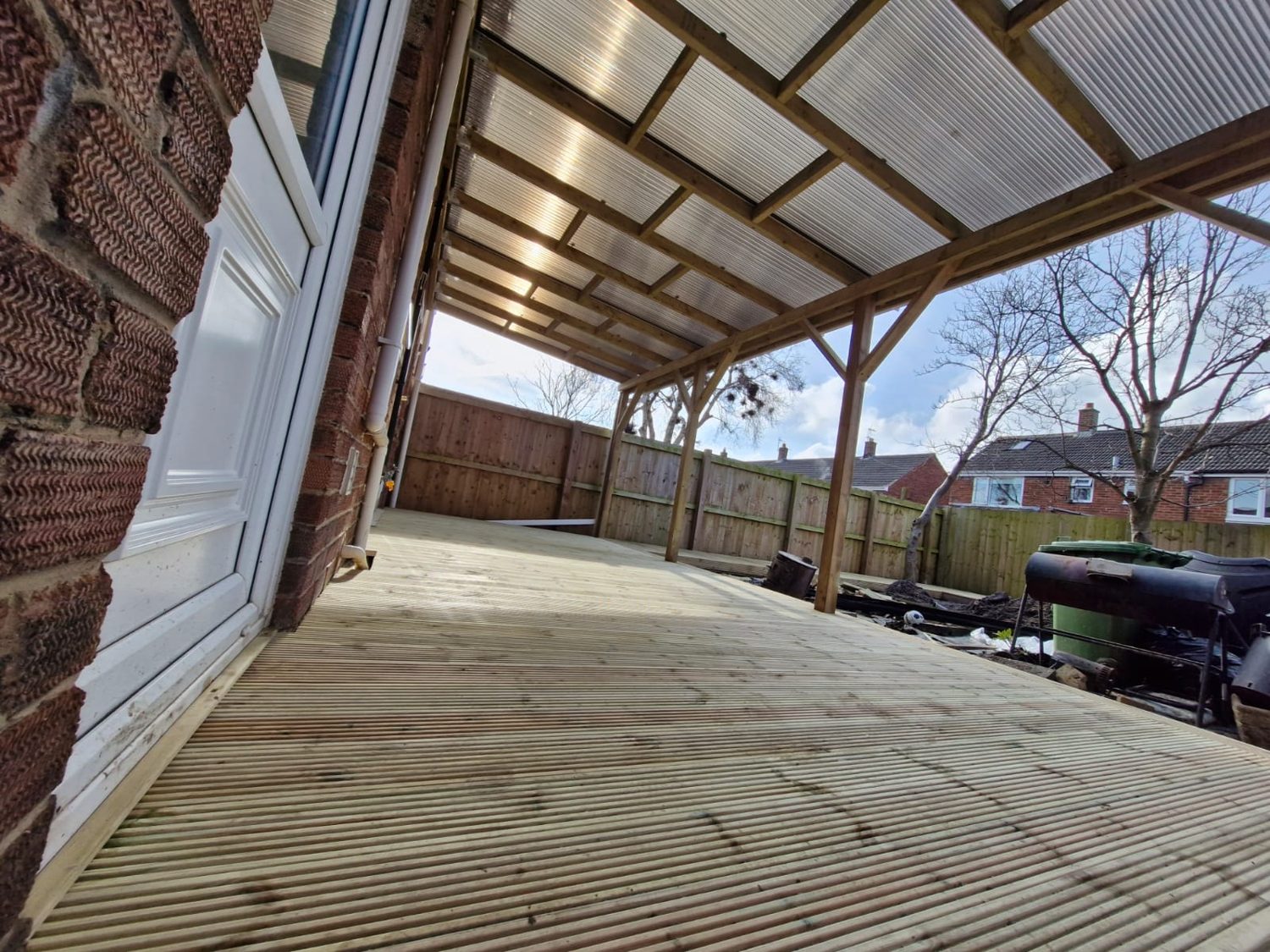 A long covered deck under a clear roof along the back of a house